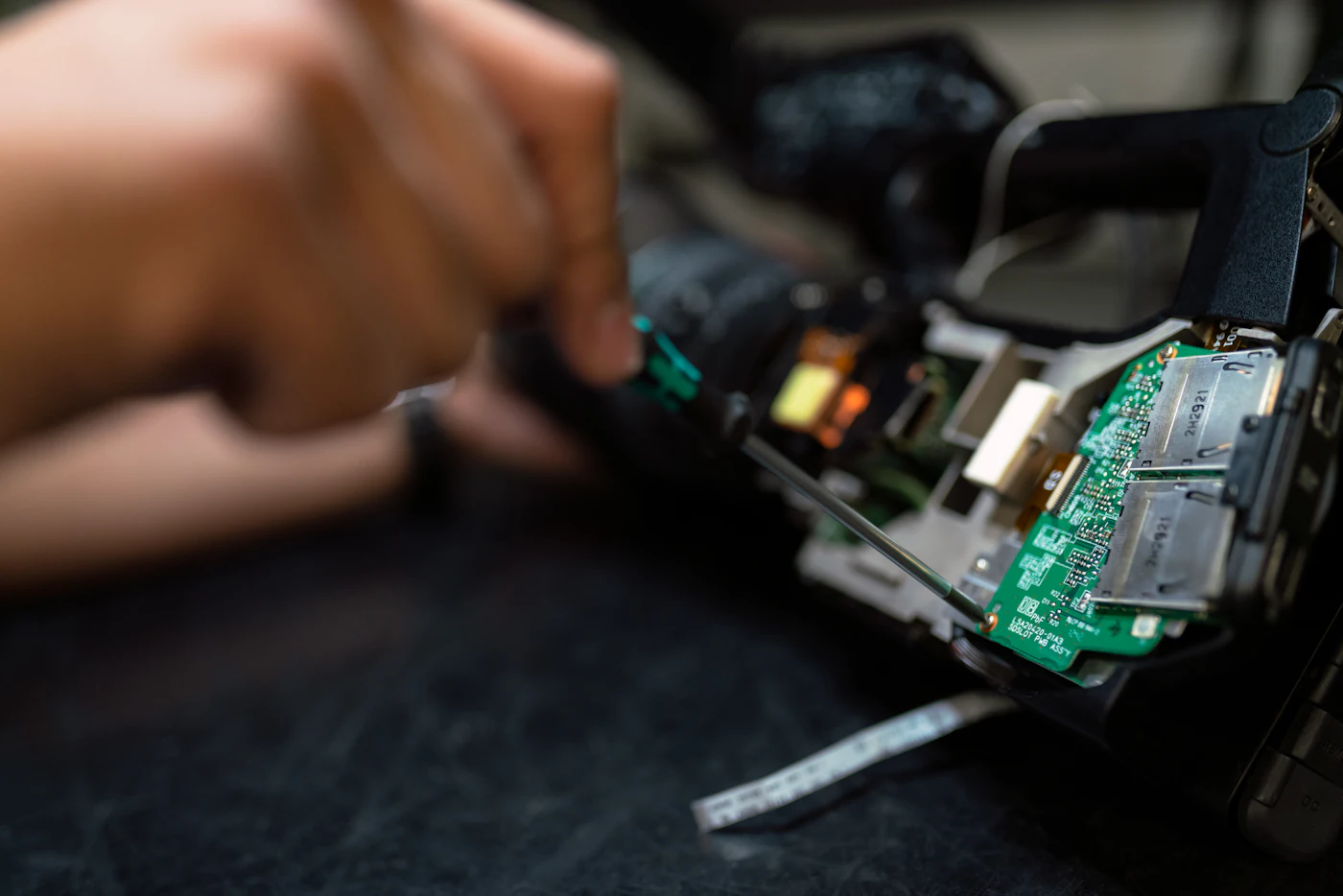 Hands assembling a compact electronic module with a screwdriver.