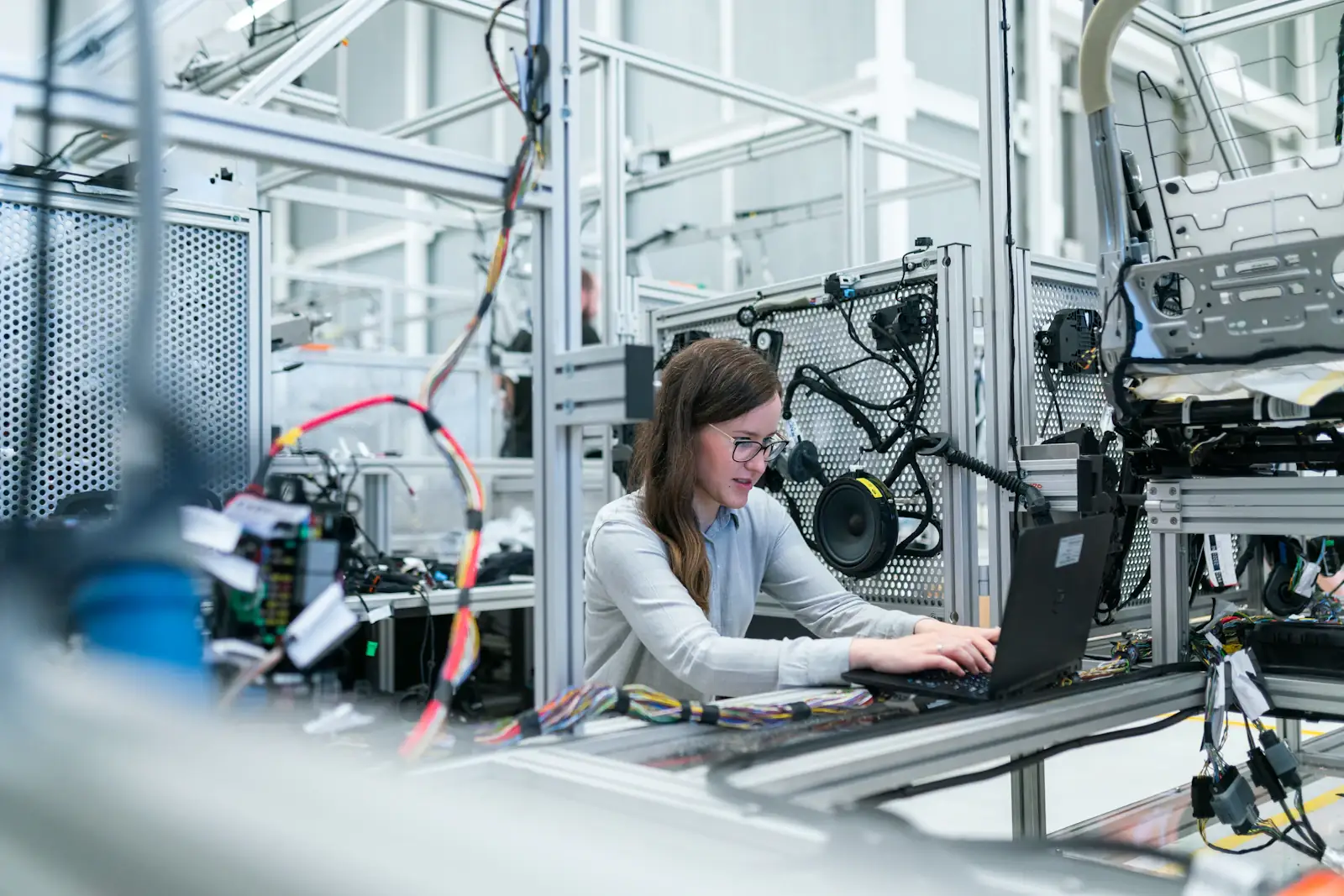 An engineer working at a laptop inside a robotics lab surrounded by test rigs and equipment.