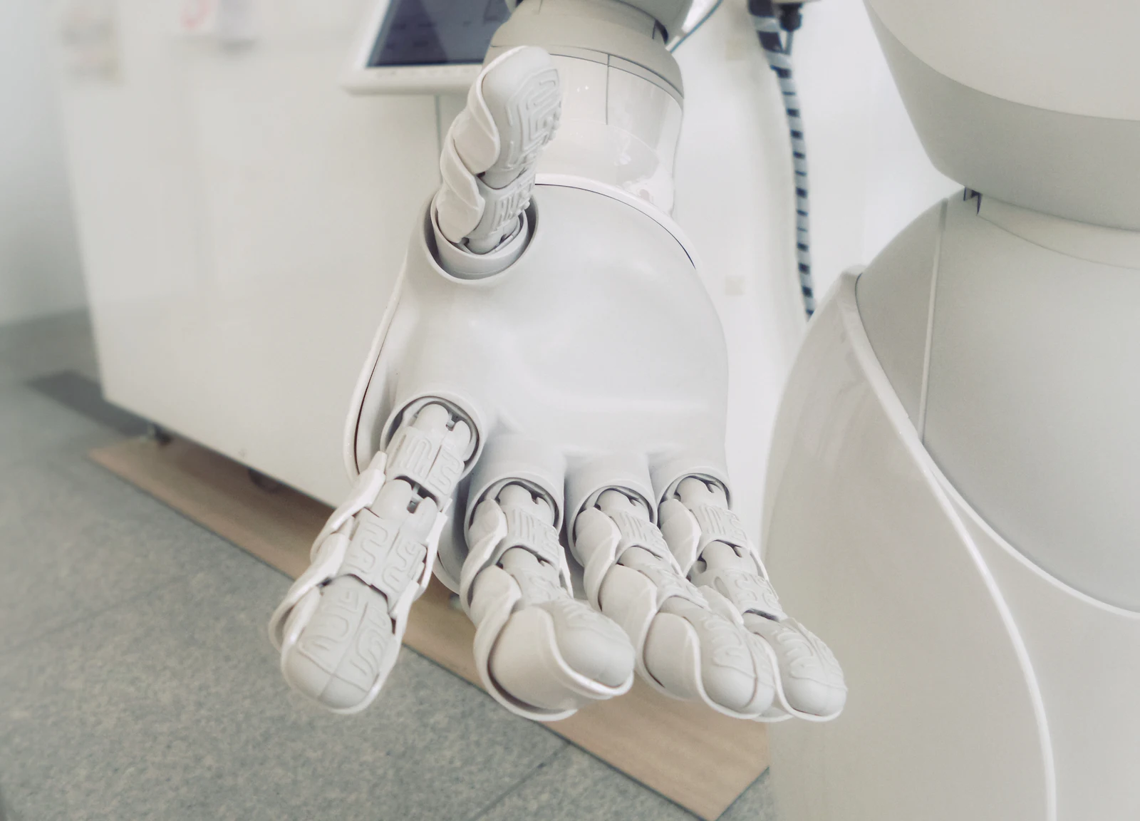 A white robotic hand with articulated fingers held open, palm facing the camera.